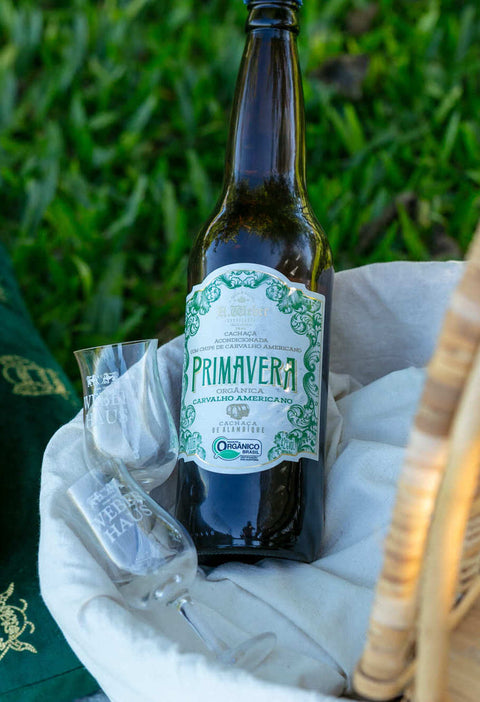 Garrafa de Cachaça Primavera Carvalho Americano 600ml acompanhada de duas taças.