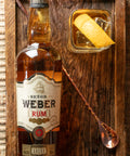 Garrafa de Rum Oro Señor Weber ambientada com um copo de drink.